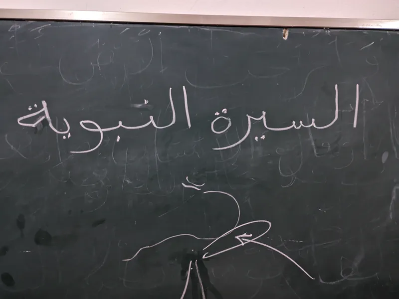 The words al-Sirah al-Nabawiyyah written in chalk on a blackboard